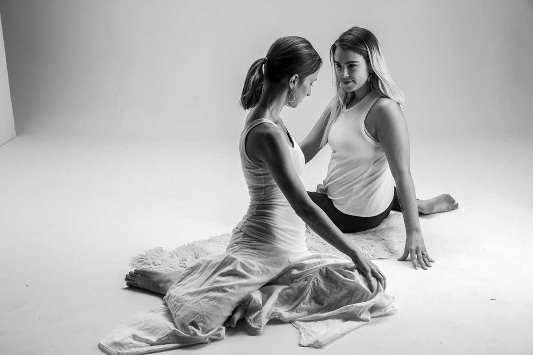 Black and white picture of Kari Kwinn and Amber in deer pose. The two are facing one another.